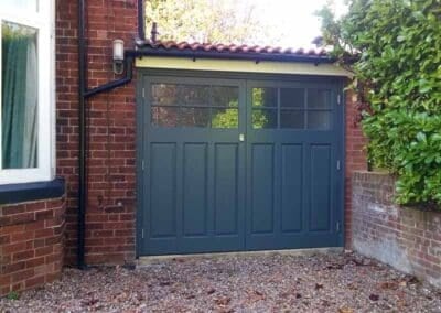 Wooden side hinged garage door painted in grey with windows